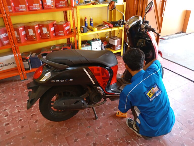 Seorang lelaki sedang memperbaiki aki pada motor
