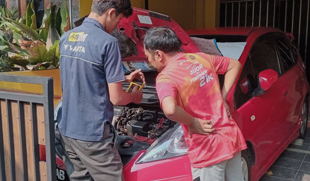 Seorang teknisi sedang memperbaiki aki mobil lemah customer