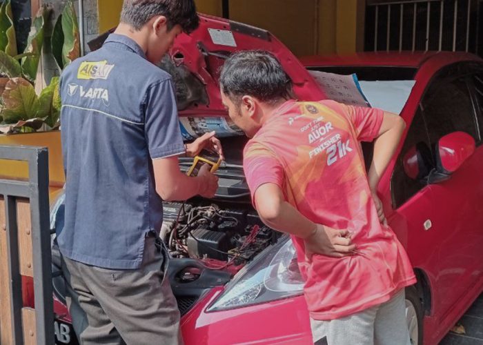 Seorang teknisi sedang memperbaiki aki mobil lemah customer